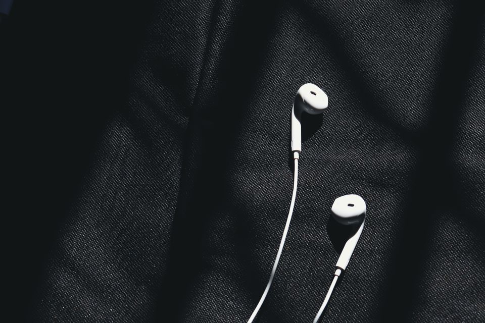 Ein ungdom lyttar til musikk med kvite leidningshøytelefonar.