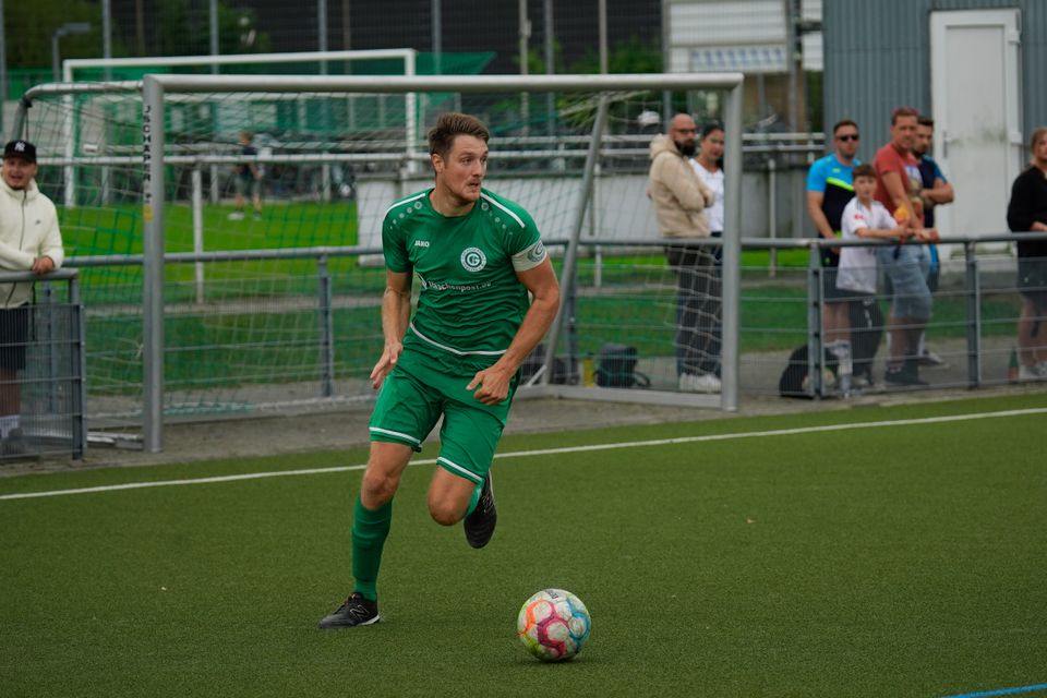 Fotballspelar i kvit trøye sparkar ballen på grønt grasmatta.